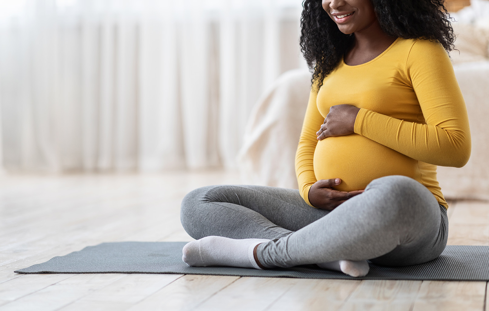 Pregnant,African,American,Woman,Sitting,On,Yoga,Mat,In,Living